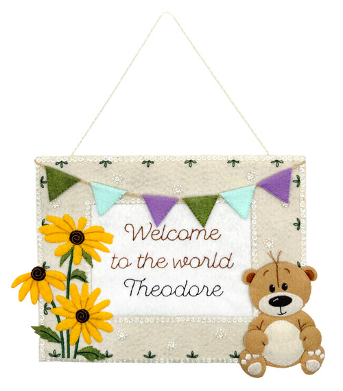 Neutral Baby Welcome TailoredExpressions felt wall hanging with bear, floral accents, banner garland, and personalized name/date.