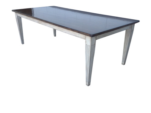Full view of Country French dining table with walnut-stained top and distressed off-white base on hardwood floor.