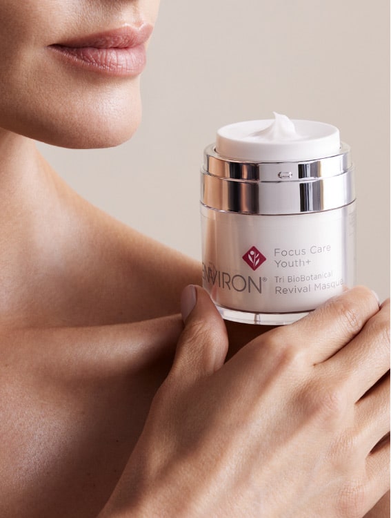 Person holding a jar of Environ Focus Care Youth+ Tri-Botanical Revival Masque near their shoulder.
