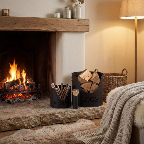 Black finish logs and kindling buckets with matchstick holder set beside an open fireplace with oak beam mantel