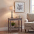 Incia column table lamp lit on a side table beside an armchair with framed art