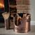 Copper finish matchstick holder and kindling bucket beside a lit wood-burning stove and exposed brick chimney
