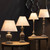 Incia urn wooden table lamp lit alongside other lamps from the Incia collection