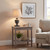 Incia urn wooden table lamp lit on a side table beside an armchair with framed art