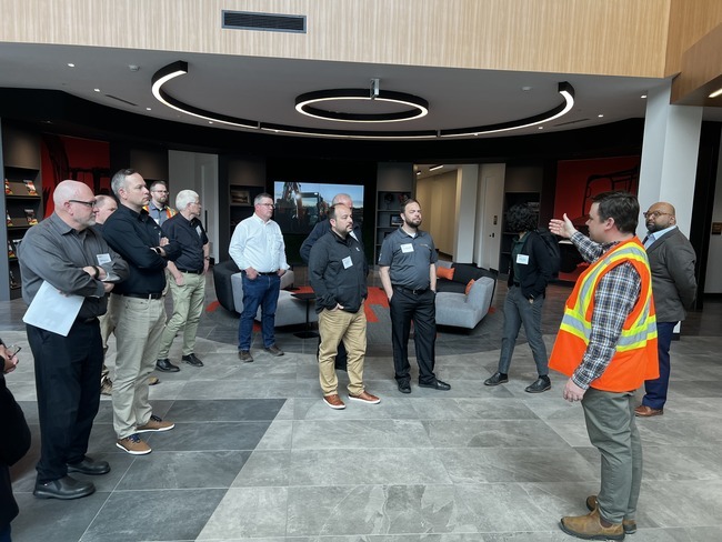 Industry professional in safety vest speaking to business leaders