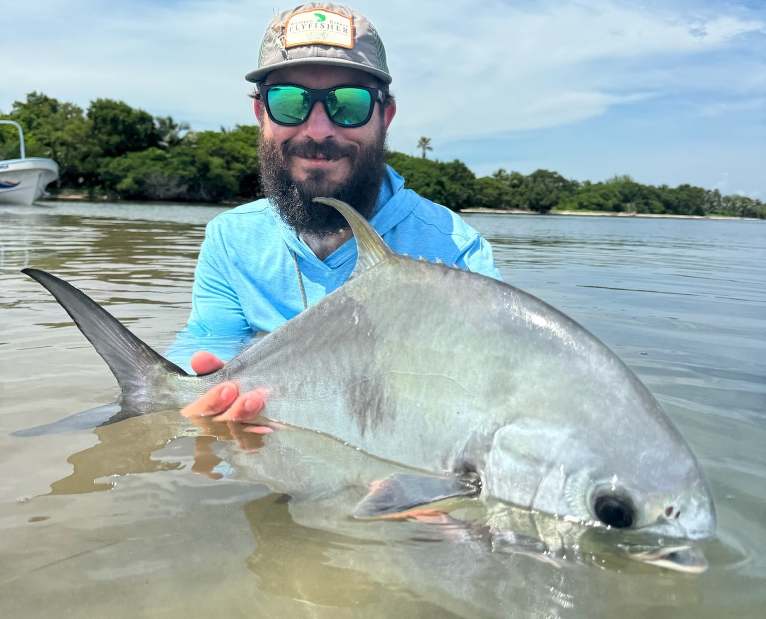 Angler holds a large Permit next to friends while Fly fishing in Mexico.