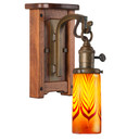  An Arts & Crafts wall sconce light fixture with a wood backplate featuring rounded corners and ebony peg accents. The lantern has a turn key socket and an aged patina finish. It has an illuminated, cylindrical blown glass shade with red feather design.