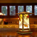  A rustic style portable table lamp with butterfly accents sits illuminated in the living room of a historic home.