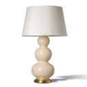  A bone colored Mid-Century table lamp featuring a glossy base with three stacked bulbous sections. The lamp is mounted on a polished brass round pedestal and topped with a slightly tapered off-white fabric drum shade.