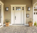  A pair of flush mounted, art nouveau wall sconce lights with an aged patina finish, white glass and a hummingbird filigrees flanking a porch door above a coordinating mailbox and potted sage.