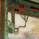  Detail of a horizontal brass blacker house mailbox with an aged new verde finish and warm iridescent glass with red and green accents.