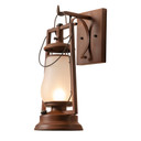  A rustic reproduction of a 19th-century, Dietz hot blast wall mounted sconce lantern on a hooked arm and scroll. The lantern looks like it's from the frontier days of the Wild West with a rusted finish and frosted shade.