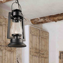  A rustic reproduction of a 19th-century, Dietz cold blast chain mounted pendant lantern from the frontier days of the Wild West with a black finish and clear glass shade. The light is hanging in a room with adobe walls and exposed wood beams and doors.