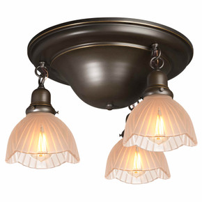  A traditional, Victorian transitional Craftsman style ceiling light fixture with an oil rubbed bronze finish and three hanging lanterns. The lanterns have scalloped glass shades in an Art Deco pattern.
