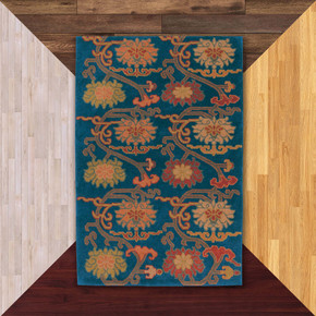  A wool rug featuring a traditional Tibetan-inspired floral design with large, stylized blossoms in warm shades of terracotta, rust, and mustard yellow. It's on a background of floor color samples.