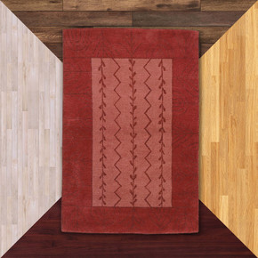  An Americana-inspired handcrafted wool rug with a floral or grain design in an earthy red and pink palette. It's on a background of floor color samples.