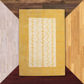  An Americana-inspired handcrafted wool rug with a floral or grain design in yellow and cream palette. It is on a background of floor color samples.  
