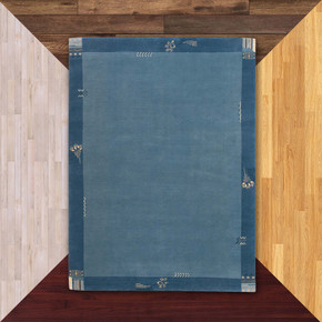  A rectangular, wool Prairie School style rug in two shades of muted blue. It's on a background of floor color samples. 