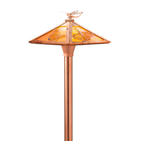  Closeup of an artistic, pyramidal garden and pathway light with a raw copper finish, golden glass and butterfly artwork. The lantern also has a dragonfly finial on the roof peak.