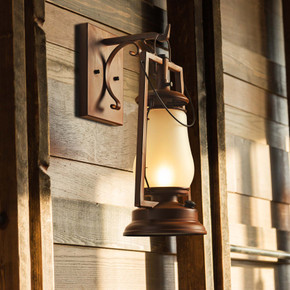  An antique-style hanging lantern sconce with a glowing frosted glass shade, mounted on a rustic weathered wood plank wall.