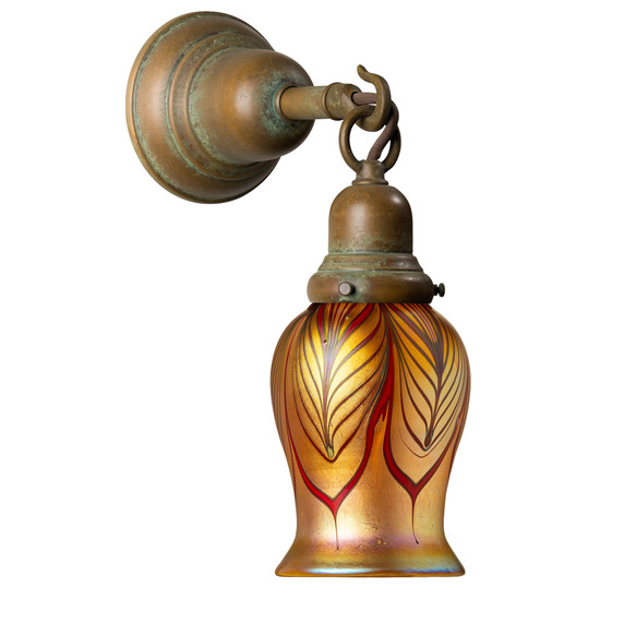  A Craftsman style wall sconce with a hook on the arm, an aged patina finish and a tulip-shaped blown glass shade with red feather design.
