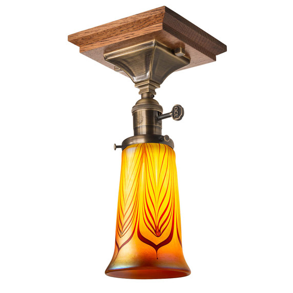  An Arts & Crafts, semi-flush ceiling mounted lantern with an aged brass finish, a turn key socket and an illuminated, trumpet-shaped blown glass red feather shade. The ceiling plate is Stickley-inspired quarter sawn oak.
