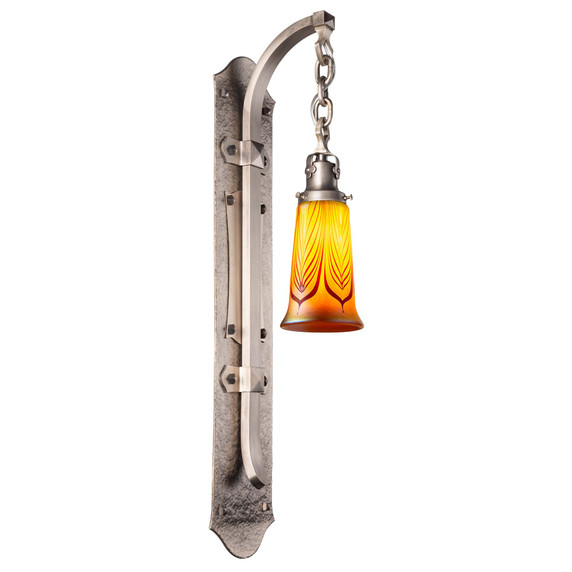  Tudor Revival or early-20th-century style wall sconce with hand-hammered pewter backplate featuring curved arm and a warmly lit blown glass shade with feathered pattern. 
