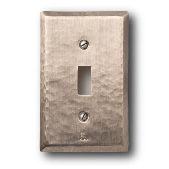  A hammered brass, single toggle switch plate cover with a glossy pewter or nickel finish.