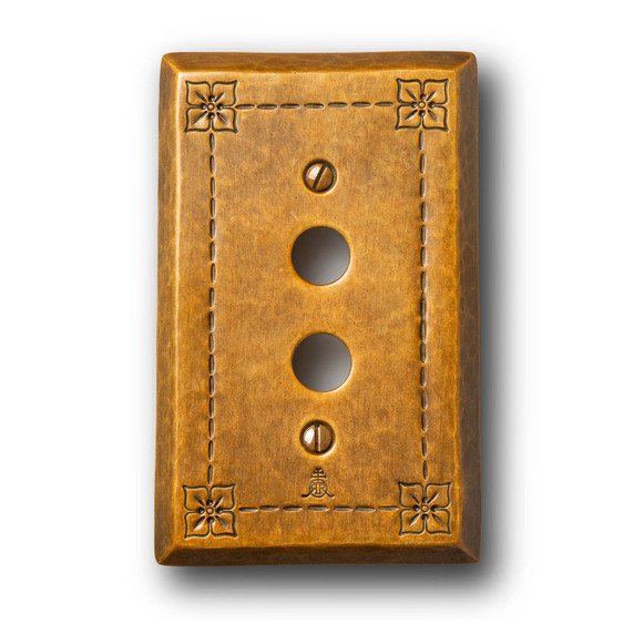  A hammered brass, push-button switch plate cover with a warm patina finish.