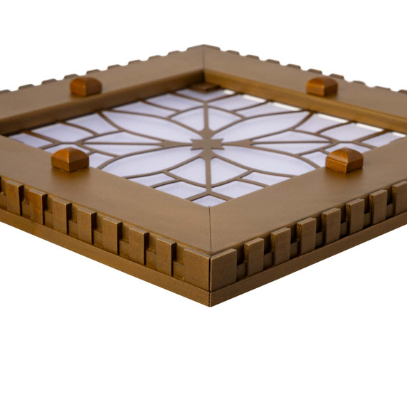  Corner detail view of a square can or recessed light cover with a dental pattern and filigree in an antique brass finish.