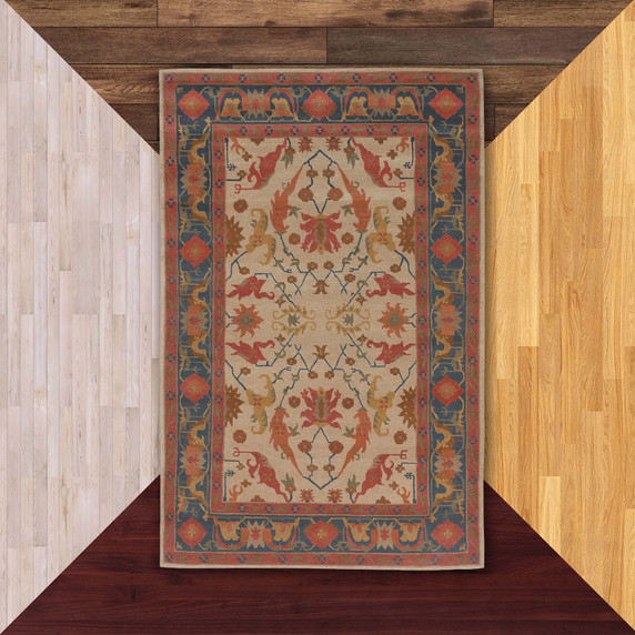  A decorative Victorian or Tudor area rug features a symmetrical design with stylized floral motifs in warm tones of red, gold, and blue on a light background. A bold navy border with geometric and floral accents frames the intricate central pattern, giving it a classic, traditional look.