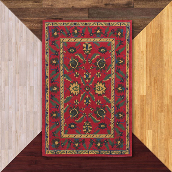  A rectangular oriental red rug with a complex floral pattern. The center is filled with large, symmetrical flower and leaf shapes in green, yellow, and blue. It is on a background of floor color samples. 