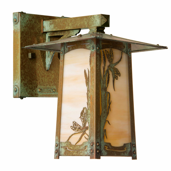  A rustic, artistic arm mounted wall sconce light fixture with a peaked roof, dragonfly artwork, an aged patina finish and warm white glass.