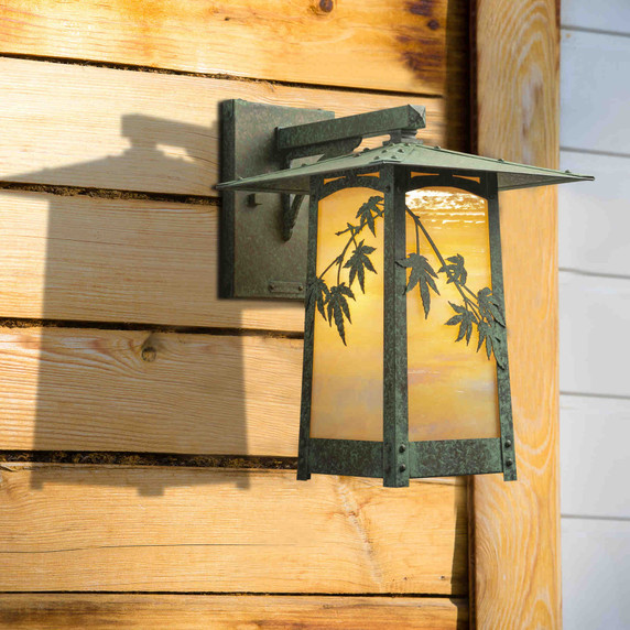  A rustic, artistic wall mounted light fixture with Japanese Maple artwork, an aged verdigris finish and golden glass installed on a wood slat wall.