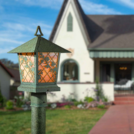  A traditional style, patinated lantern with climbing ivy artwork on a post in front of a storybook cottage home.