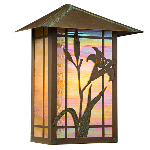  A tall, flush mounted wall sconce lantern with a peaked roof, aged patina finish, iridescent glass and lily artwork.