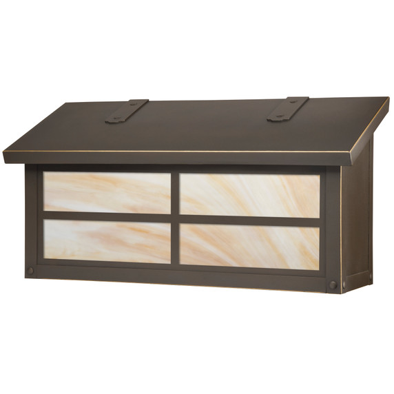  A brass mailbox with a bronze finish, warm white glass and a cross window pattern.