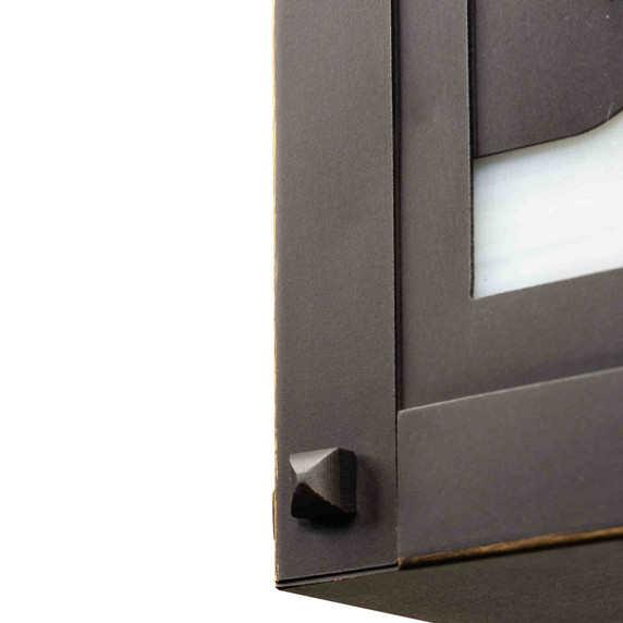  Detail corner rivets of a horizontal brass blacker house mailbox with an bronze finish and warm toned glass with red and green accents.