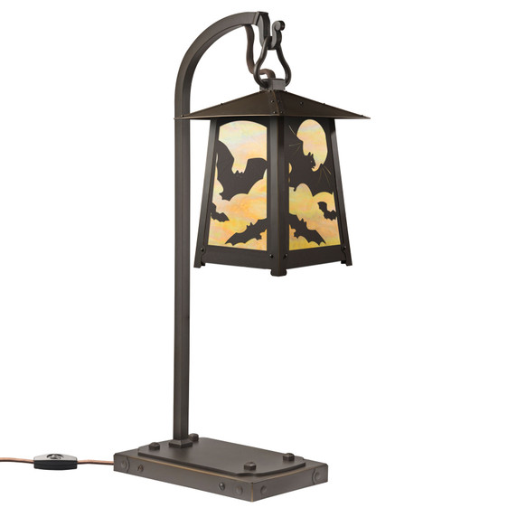  A beefy, rustic table lamp on a hooked arm with Halloween or horror film artwork of flying bats, an oil-rubbed bronze finish and iridescent glass.