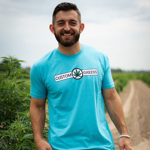 This image showcases a Custom Greens blue t-shirt, the perfect blend of comfort and style. The t-shirt features a rich shade of blue, mirroring the tranquility and relaxation associated with our premium CBD products. Made from top-quality cotton fabric, it offers a soft and comfortable feel against the skin. On the front, you'll find the Custom Greens logo, a symbol of trust and quality in the CBD industry. This blue t-shirt is not just apparel; it's a statement of your commitment to well-being and excellence. Elevate your CBD experience and express your support for Custom Greens with this exclusive piece of attire.