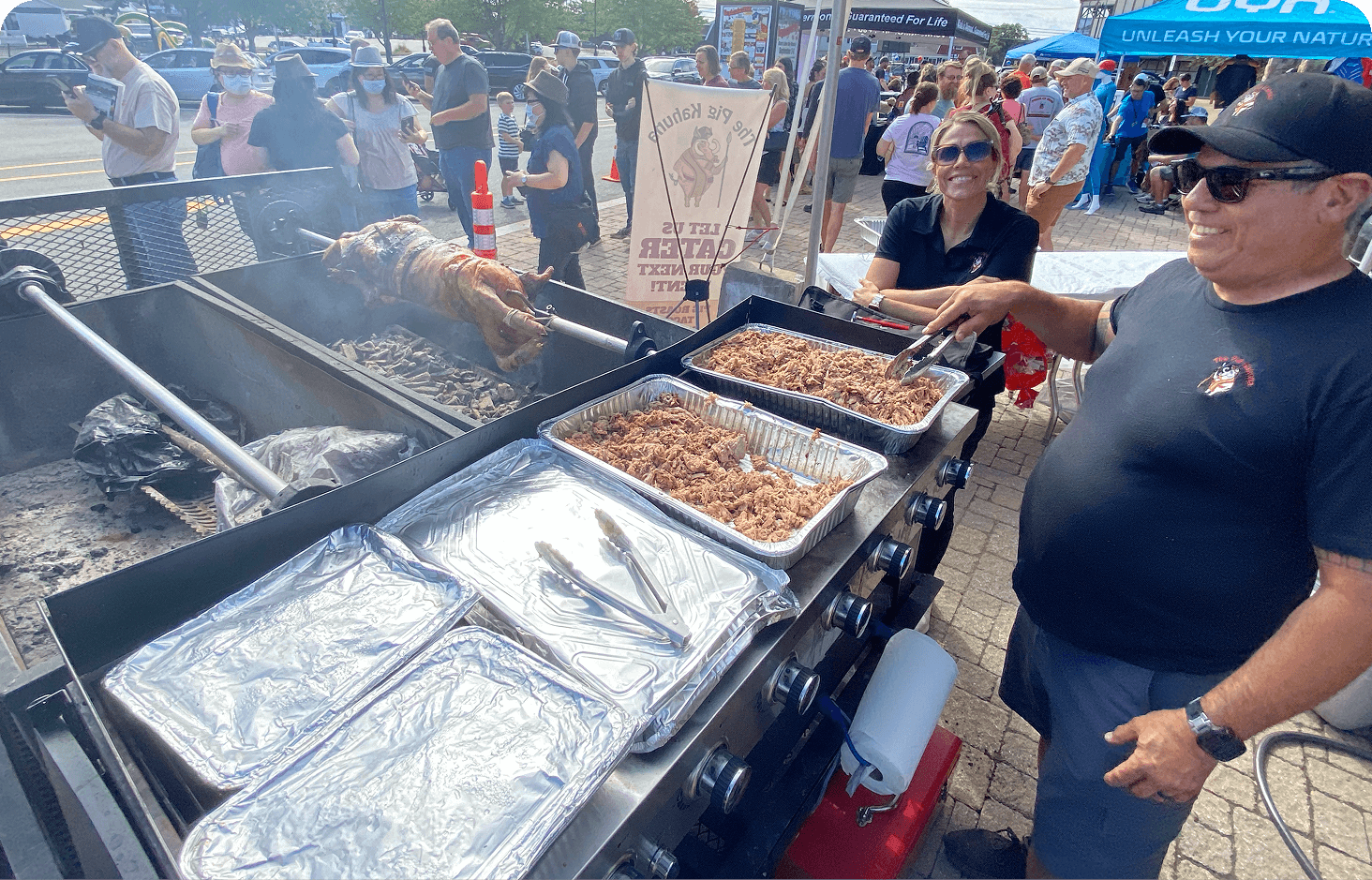 Smiling people grilling pig on Pig Kahuna BBQ