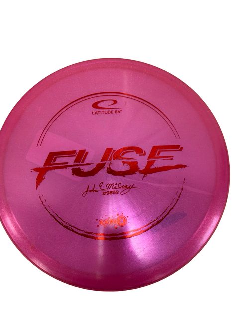Vist Large View of Product Image Which is Used Latitude 64 FUSE John E McCray Opto X Glimmer Golf Disc Midrange Pink 179g