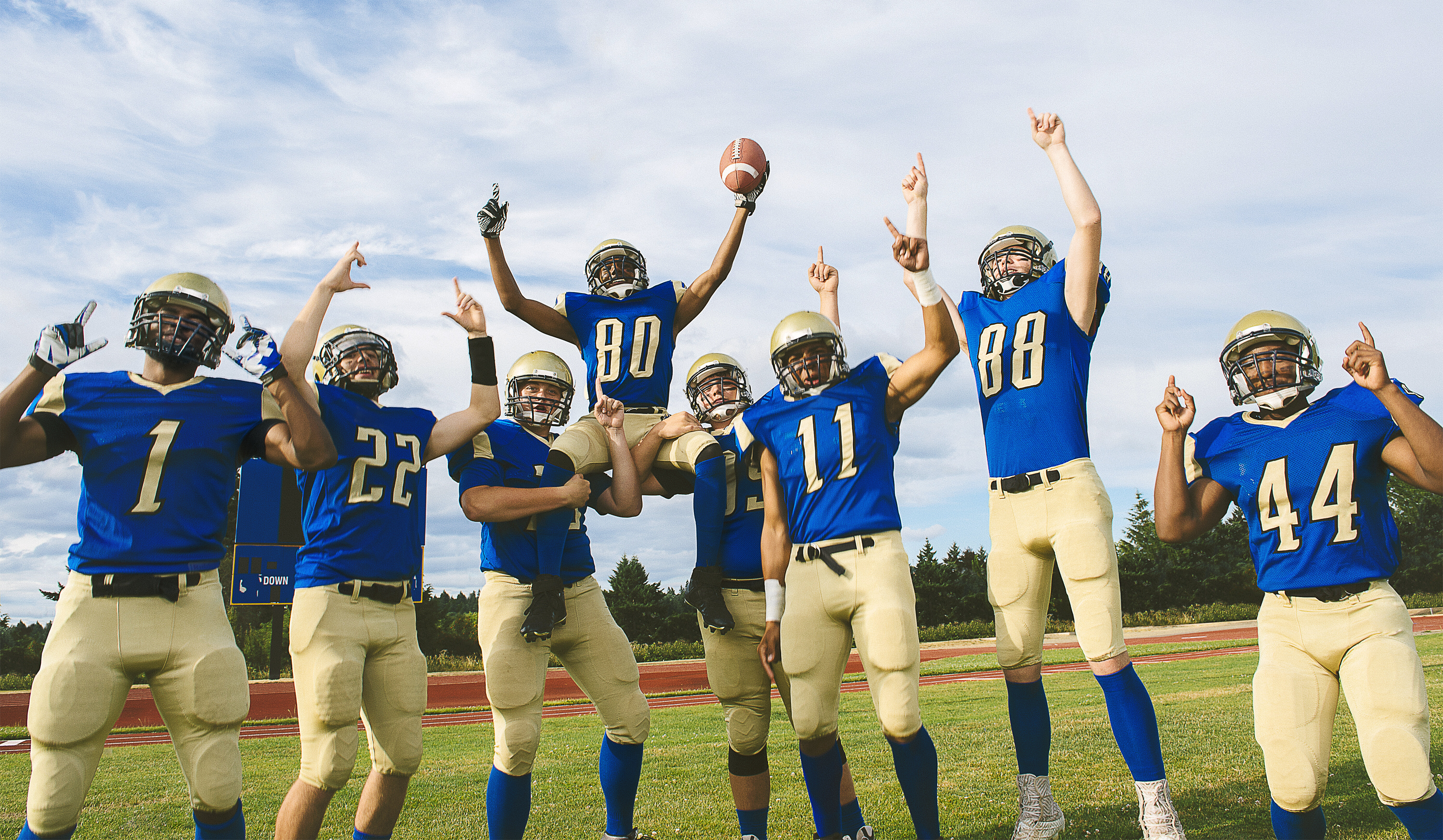 Youth football team wearing matching uniforms celebrating together on the field