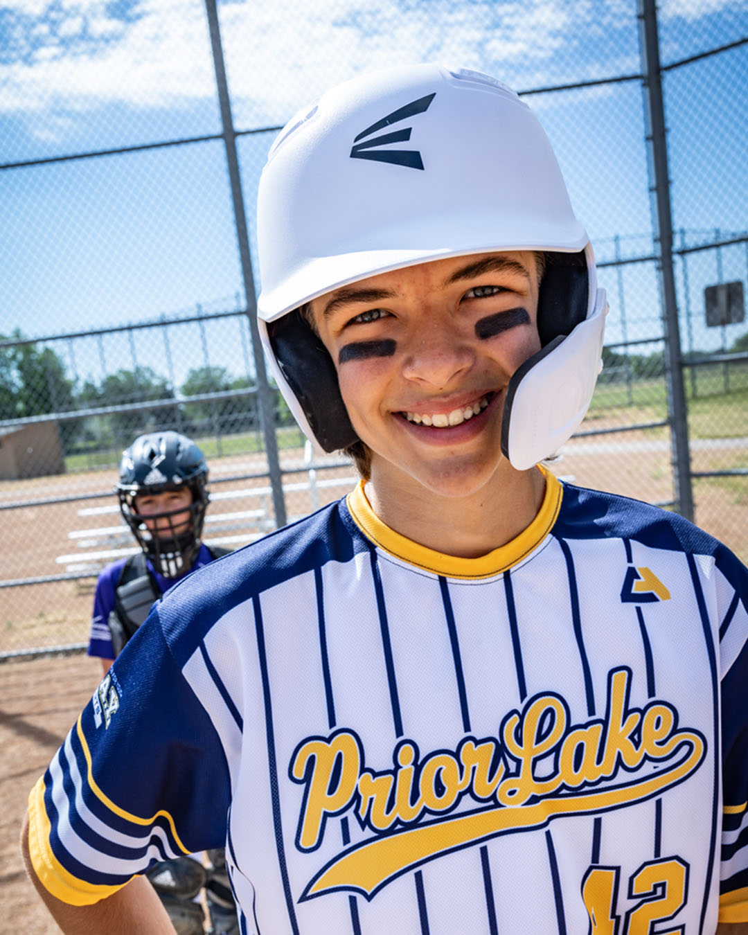 image of young male baseball player with white easton baseball helmet on