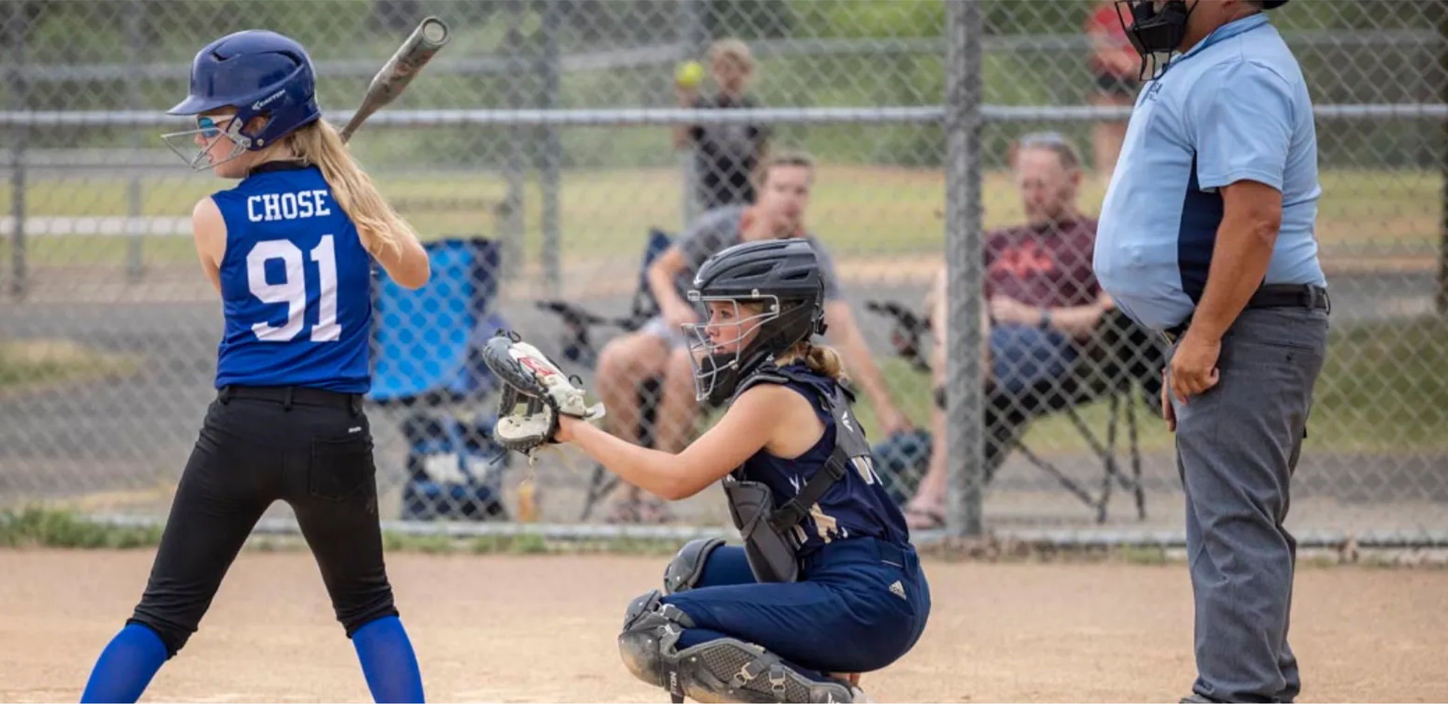 Young softball player at bat with spectators in the background