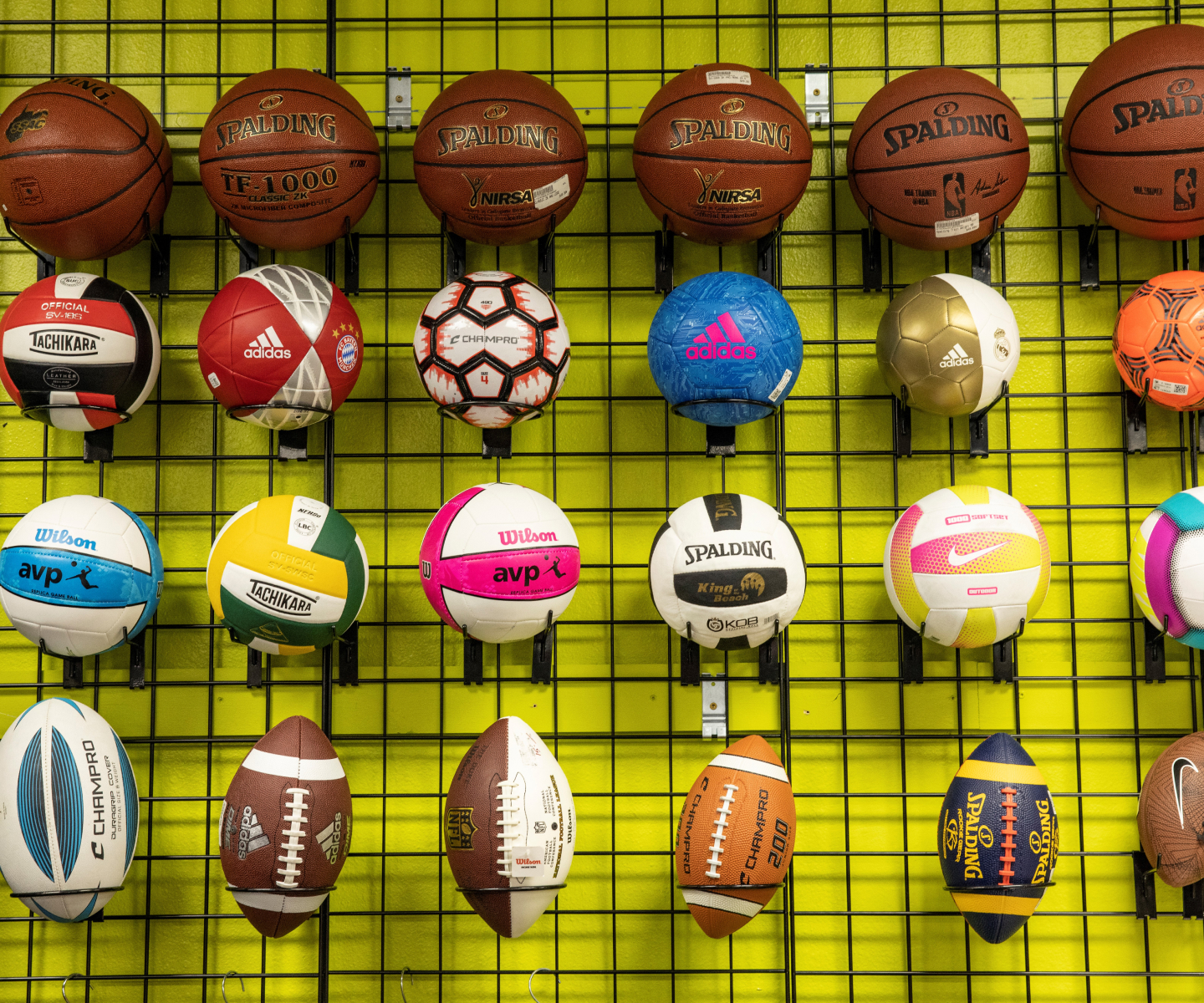 soccer balls, footballs, and basketballs displayed on a store wall