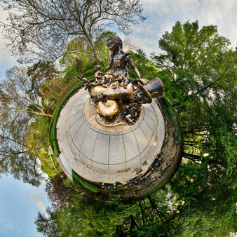 An early morning 360-degree panoramic spherescape of the 'Alice in Wonderland' statue in Central Park, surrounded by lush greenery and the soft light of dawn.