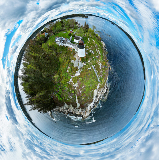 360 panoramic image of Burnt Island Light near Boothbay Harbor, Maine, showcasing the lighthouse surrounded by lush greenery and calm blue waters under a sweeping sky