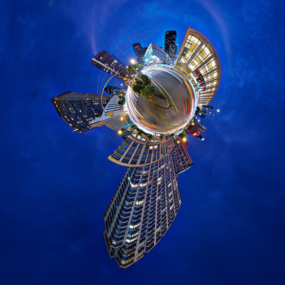 A 360-degree panoramic nighttime image of Lincoln Center in NYC, with the center's illuminated buildings dramatically arching over the scene set against a deep blue night sky.