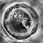 Aerial black and white infrared 360-degree panoramic photograph of Cundy's Harbor, Maine, showcasing a spherical perspective with a striking contrast between the dark waters, light-toned boats, docks, and ethereal trees under a textured sky